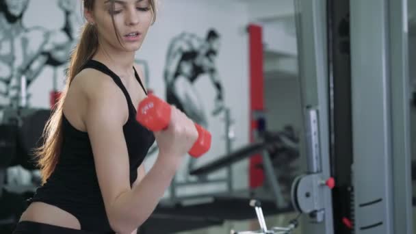 Güzel esmer bir egzersiz dumbbells ile gerçekleştirir. 4k — Stok video