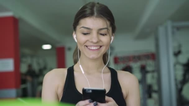 Primer plano de una chica con auriculares en una cinta de correr. 4k — Vídeo de stock