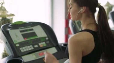 Bir kızın bir koşu bandı üzerinde kulaklık ile yakın çekim. 4k