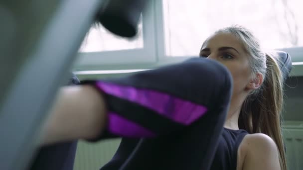 Nahaufnahme einer attraktiven jungen Frau, die sich auf ihre Beinpressübungen konzentriert. 4k — Stockvideo