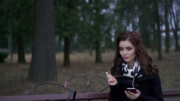 Piękna dziewczyna słucha muzyki w parku — Wideo stockowe