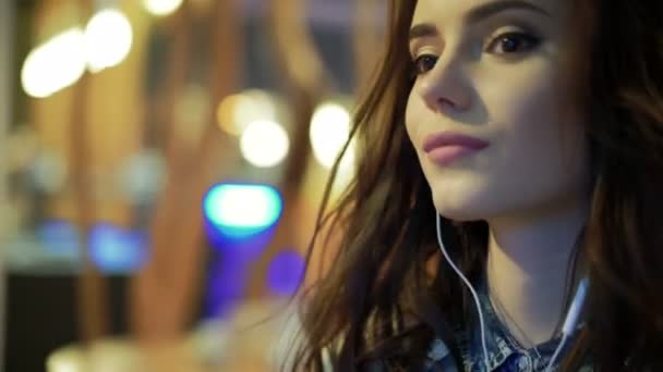 Mooi meisje luistert naar muziek in een café — Stockvideo