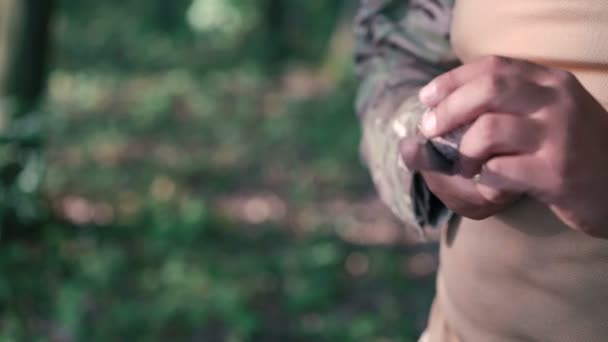 Close up de soldado afiar faca com pedra de bilestone na floresta — Vídeo de Stock