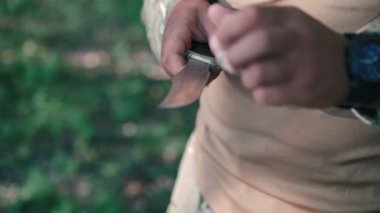 Askerin yakın bilestone ormanın içinde bıçak keskinleştirmek. Ağır çekim