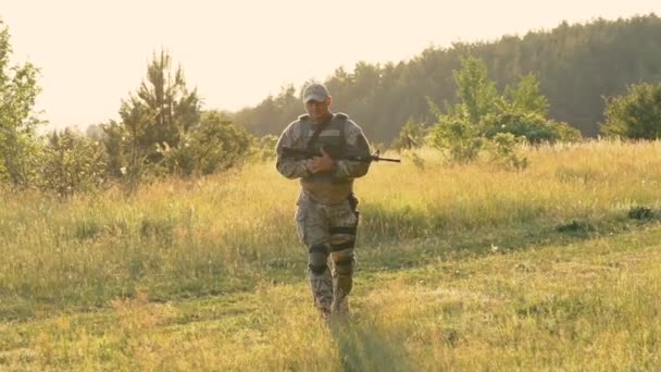 Militaire man met automaat in handen gaat op het pad. Langzaam — Stockvideo