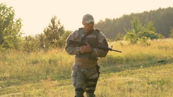 Soldado cansado con autómata en las manos va en el camino. Despacio. — Vídeo de stock