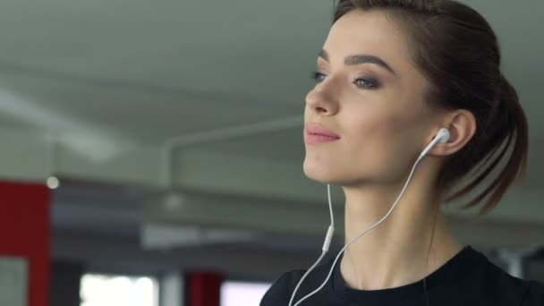 Close-up van een meisje met een koptelefoon op een loopband. Langzaam — Stockvideo