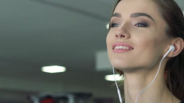 Close-up of a girl with headphones on a treadmill. Slowly — Stock Video