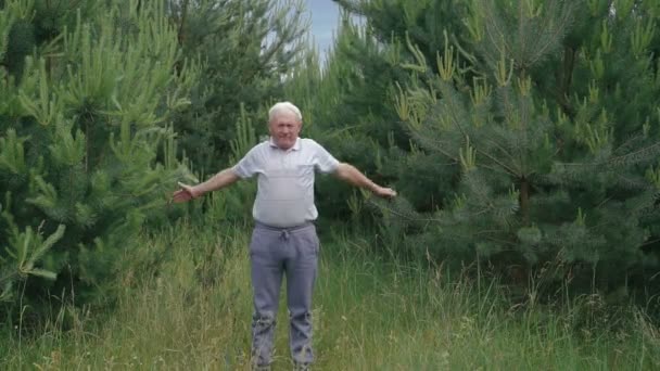 Old man does morning exercises squats up-down on the camera — Stock Video