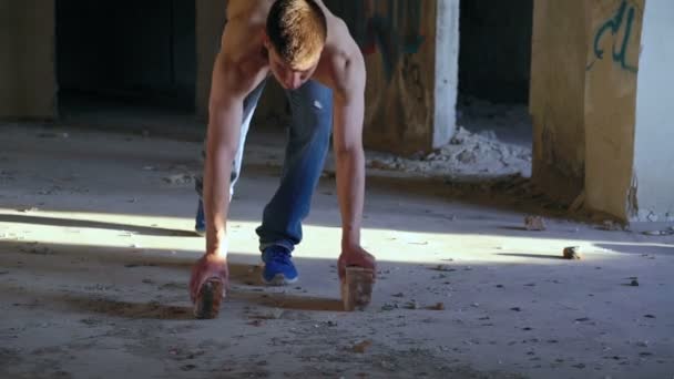Hombre fuerte haciendo flexiones con ladrillos en catacumba — Vídeos de Stock