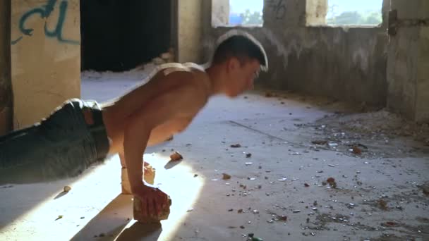 Сильный мужчина отжимается от кирпичей в катакомбе — стоковое видео