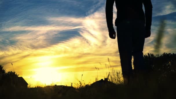 La silueta del hombre va sobre el fondo colorido del cielo. Despacio. — Vídeos de Stock