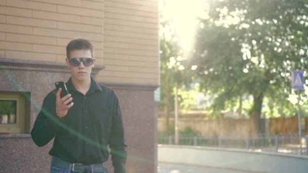 Стильный человек, курящий электронную сигарету и разговаривающий по телефону на открытом воздухе — стоковое видео