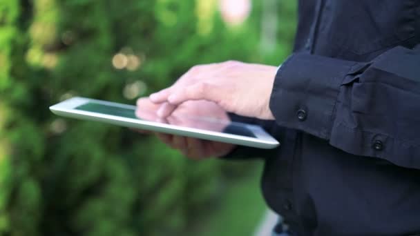 Mans rukama dotýkat a používání tabletu na pozadí Zelený strom — Stock video