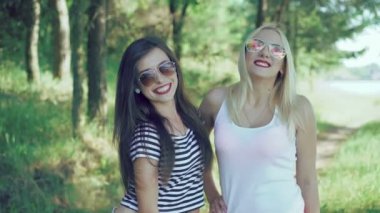 İki güzel kız parkta kamera için poz bordo dudaklı. 4k