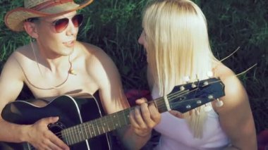 Kızlarla birlikte gülümseyen ve konuşma çimenlerin üzerinde oturan çocuk. 4k