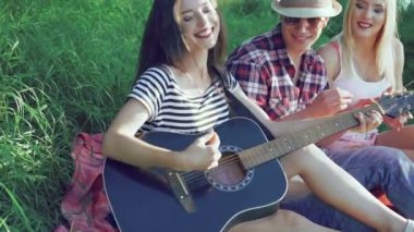 Kız çim ve alkışlar arkadaşlar üzerinde gitar çalıyor. 4k