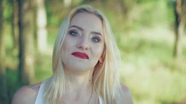 Seksi sarışın bordo dudakları ile güneş gözlüğü alır. 4k