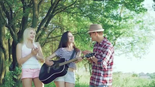 La fille joue de la guitare dans le parc et ses amis applaudissent. 4k — Video