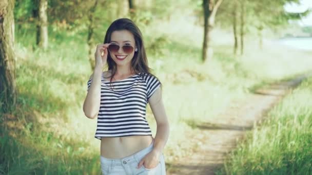 Chica de la moda coqueteando, posando y mirando una cámara en el parque. 4k — Vídeo de stock