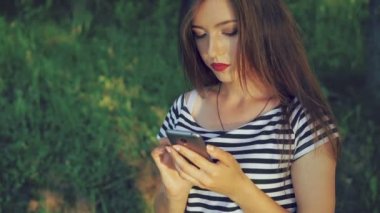 Telefon yeşil yaz parkta kullanan genç kız. 4k