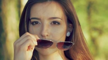 Bordo dudaklar esmer güzel güneş gözlüğü alır ve kamera üzerinde görünüyor. Yavaş yavaş