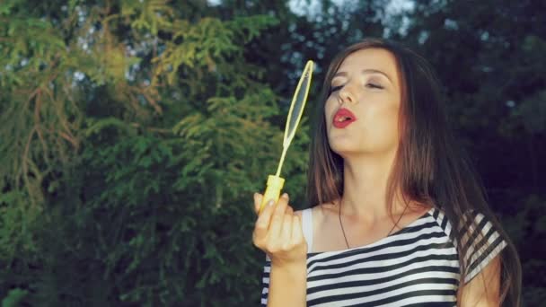 Happy brunette blowing colourful soap bubbles in summer park. Slowly — Stock Video