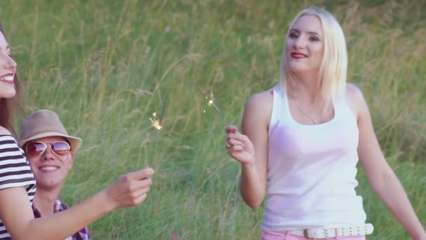 Les filles dansent avec des lumières du bengale lorsque le garçon joue de la guitare sur la nature. Doucement. — Video