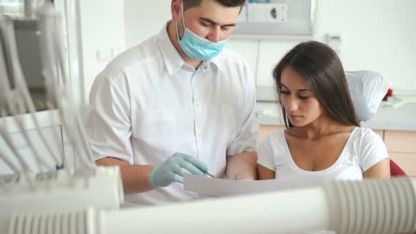 Dentista explicando procedimiento a paciente femenina en sala de dentista — Vídeo de stock