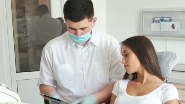 Dentista explicando procedimiento a paciente femenina en sala de dentista — Vídeo de stock