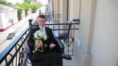Damat Düğün buket ile balkonda oturuyor. Zaman atlamalı