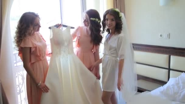 Bruden med vänner hålla bröllopsklänning i rummet — Stockvideo