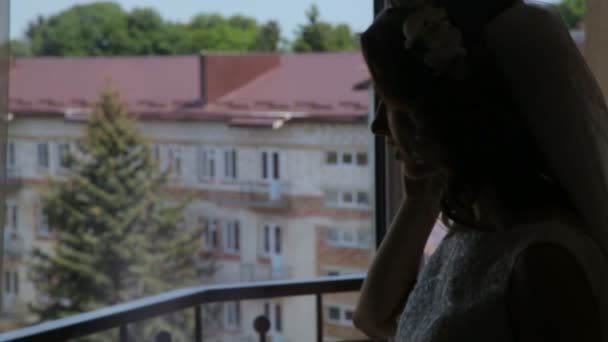 Pretty bride is speaking on the phone on the balcony in the evening — Stock Video