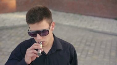 Güneş gözlüğü ve göz yanıp sönen unwearing adam e-sigara, Sigara. Yavaş yavaş