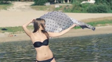 Denizde ayakta ve pareo tutan güzel kız. Yavaş yavaş