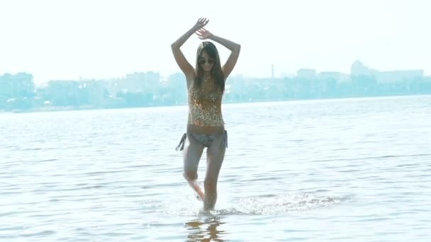 Жінка біжить і позує в річці в гламурному купальнику. Повільний рух — стокове відео