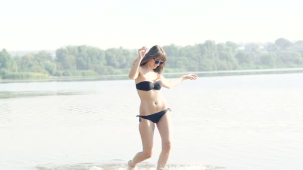 Chica bonita corriendo en el agua y las manos arriba. Despacio. — Vídeos de Stock