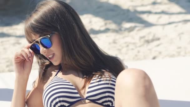 Stijlvolle meisje rusten op het zand beachs en glimlachen. Langzaam — Stockvideo