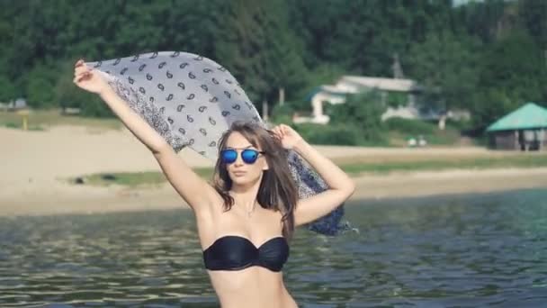 Красивая девушка, стоящая в море и держащая парео. 4K — стоковое видео