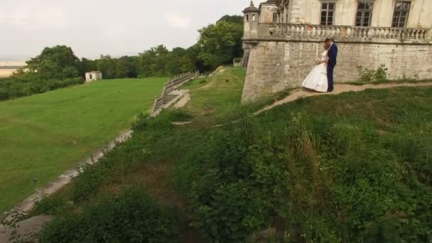 Vista aérea de um belo jovem casal em pé na encosta do castelo. 4k — Vídeo de Stock