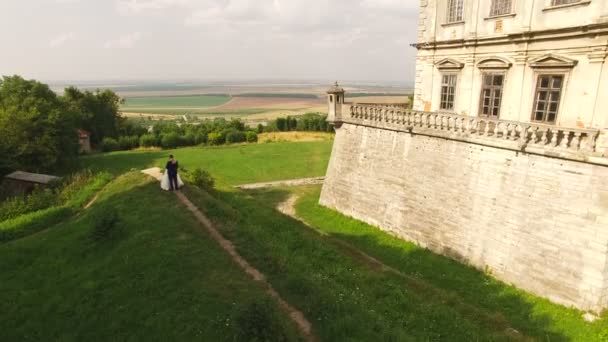 Vista aérea do jovem casal de casamentos dançando no castelo na descida. 4k — Vídeo de Stock