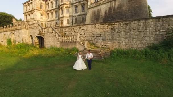 Luftaufnahme: Schönes Hochzeitspaar beim Spaziergang am antiken Schloss. 4k — Stockvideo