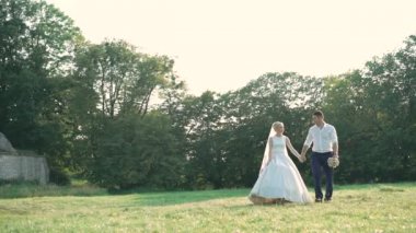 Beyaz gelin ve damat parkta yürüyüş üzerinde. Yavaş yavaş