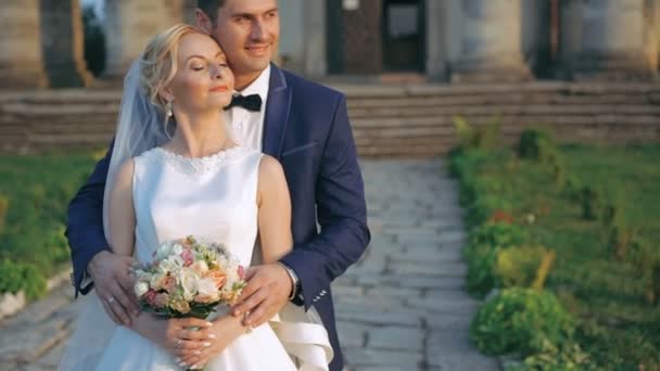 Casal de casamento feliz elegante suavemente abraçando no fundo do castelo. 4K — Vídeo de Stock