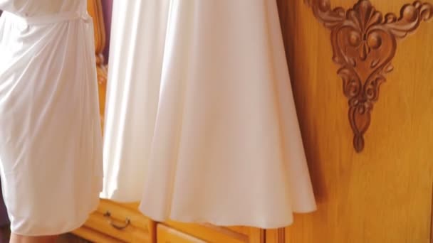 Невеста обнимает свадебное платье и улыбается в комнате — стоковое видео