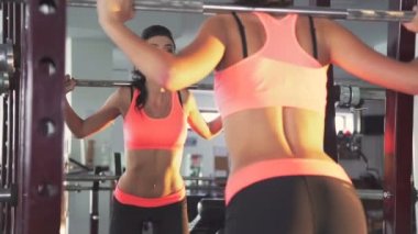 Kız ile Halter salonunda çömelme yapıyorum. Onun arkasında bir bak