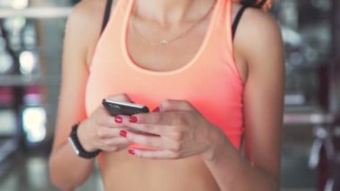 Telefonunuzun ve spor salonunda ve gülümseyen neşeli kadın