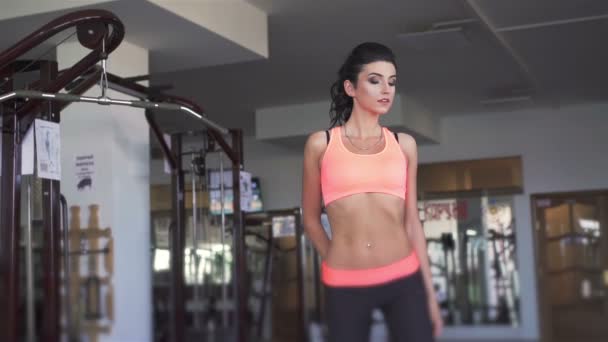 Ganska ung brunett kvinna poserar i sport gym. Slow motion — Stockvideo