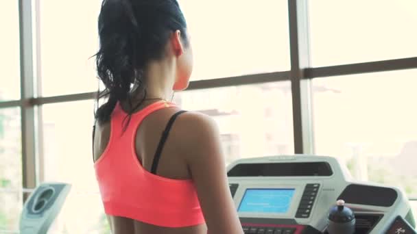 Mujer haciendo ejercicios con pista de carreras en el gimnasio. Mira detrás de la mujer — Vídeos de Stock