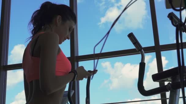 Profil de sexy girl en utilisant le téléphone dans la salle de gym près de la fenêtre — Video